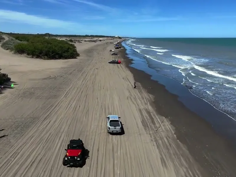 Playa de Monte Hermoso con camionetas circulando por la arena junto a los médanos